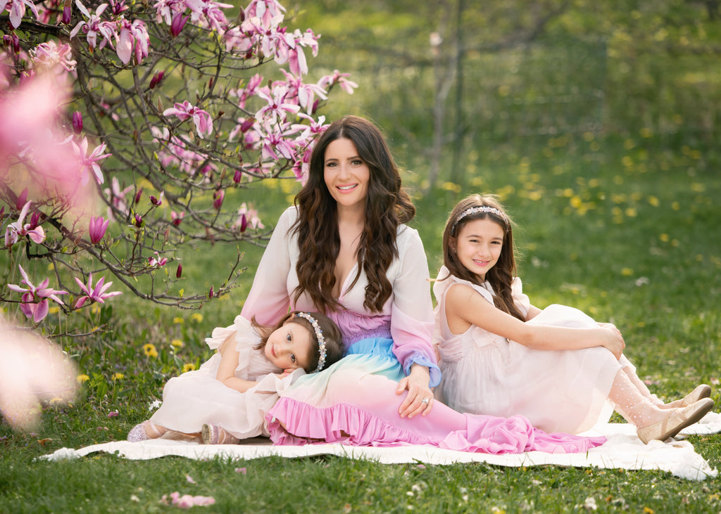 Love Peace Organic founder Anastasia Taras with her two daughters sitting on a white blanket in a lush green field
